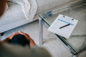 From above of blurred unrecognizable female psychologist sitting in office near table with clipboard and pen during session in office